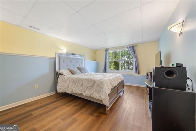 bedroom with hardwood / wood-style floors and a drop ceiling