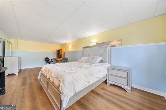 bedroom with wood-type flooring and a drop ceiling