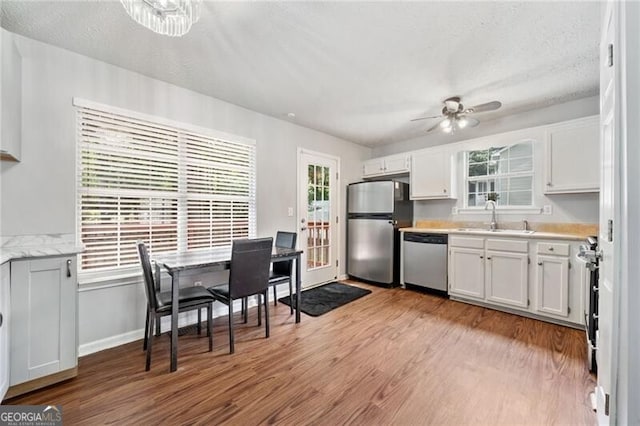 kitchen featuring sink, ceiling fan, stainless steel appliances, light hardwood / wood-style floors, and white cabinets