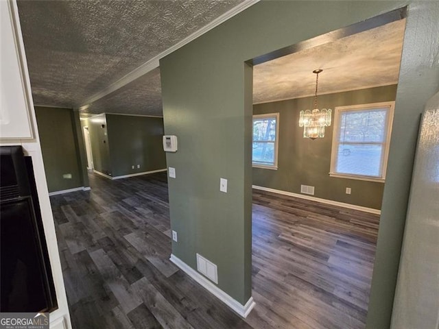 hallway featuring ornamental molding, dark hardwood / wood-style floors, a textured ceiling, and a notable chandelier