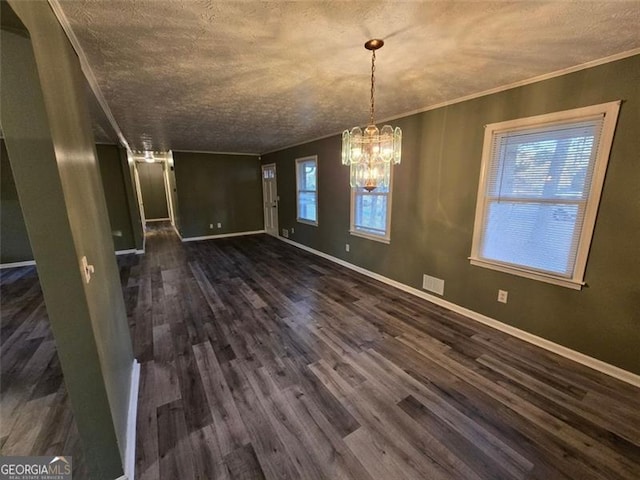 unfurnished dining area featuring an inviting chandelier, crown molding, dark wood-type flooring, and a textured ceiling