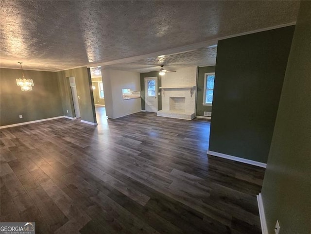 unfurnished living room featuring dark hardwood / wood-style flooring, ceiling fan with notable chandelier, a fireplace, and a textured ceiling