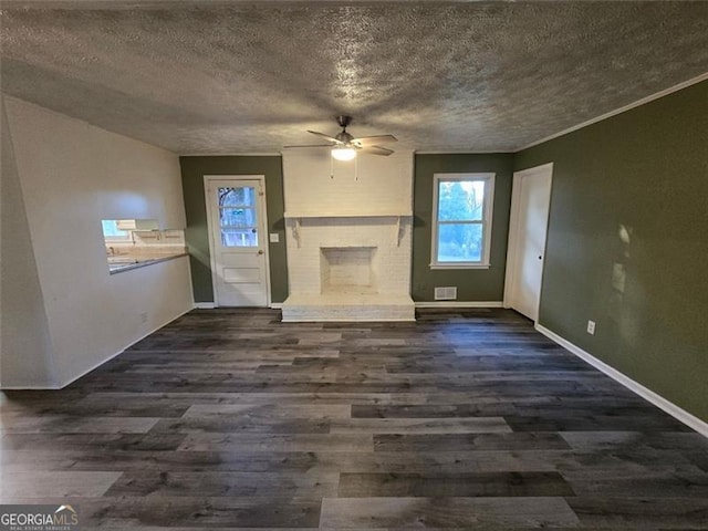 unfurnished living room with crown molding, a textured ceiling, dark hardwood / wood-style floors, ceiling fan, and a fireplace