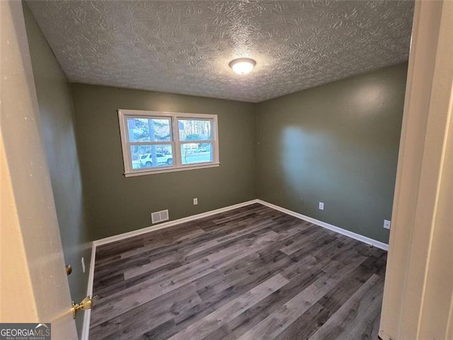 empty room with dark wood-type flooring and a textured ceiling