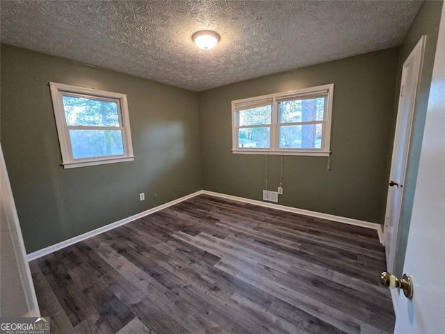 empty room with dark hardwood / wood-style flooring and a textured ceiling