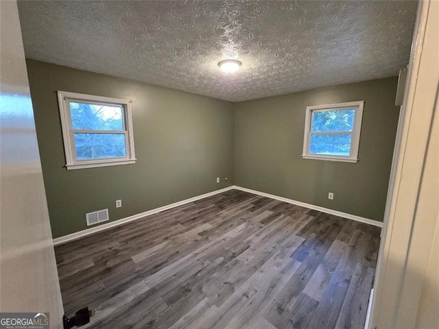 unfurnished room featuring a wealth of natural light, wood-type flooring, and a textured ceiling