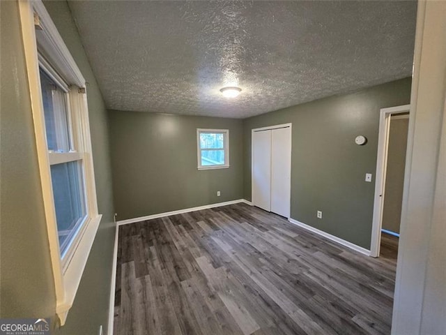 unfurnished bedroom featuring dark hardwood / wood-style floors, a textured ceiling, and a closet