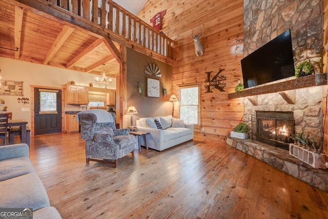 living room featuring beam ceiling, wood ceiling, light hardwood / wood-style flooring, a notable chandelier, and a fireplace