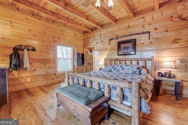 bedroom featuring beam ceiling, wooden walls, wood ceiling, and light wood-type flooring