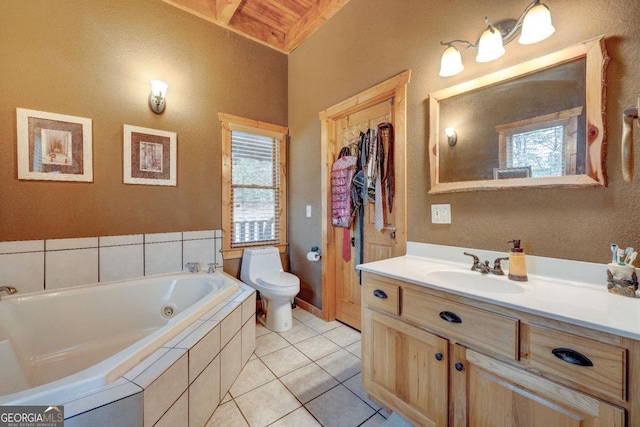 bathroom featuring tile patterned flooring, vanity, tiled bath, and toilet