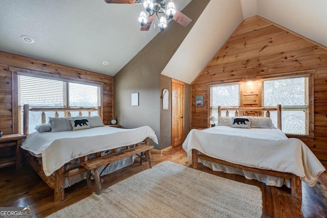 bedroom featuring multiple windows, hardwood / wood-style flooring, and wooden walls