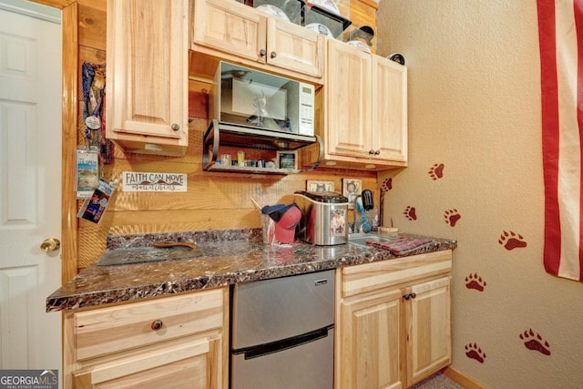 kitchen featuring light brown cabinetry and dark stone counters