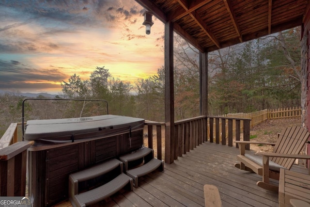 deck at dusk featuring a hot tub