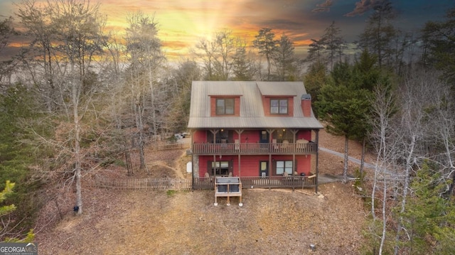 back house at dusk with a balcony and covered porch