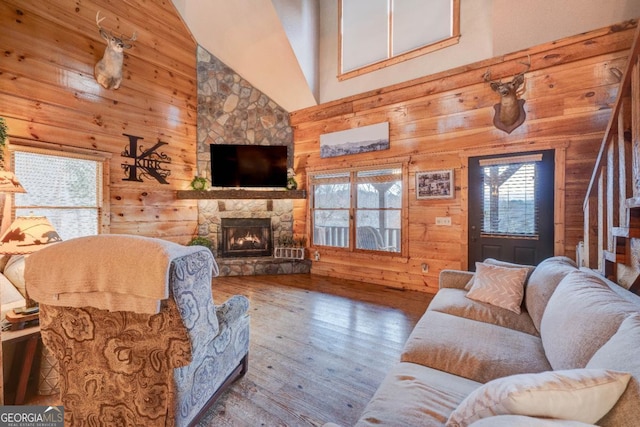 living room with a fireplace, wooden walls, and a healthy amount of sunlight