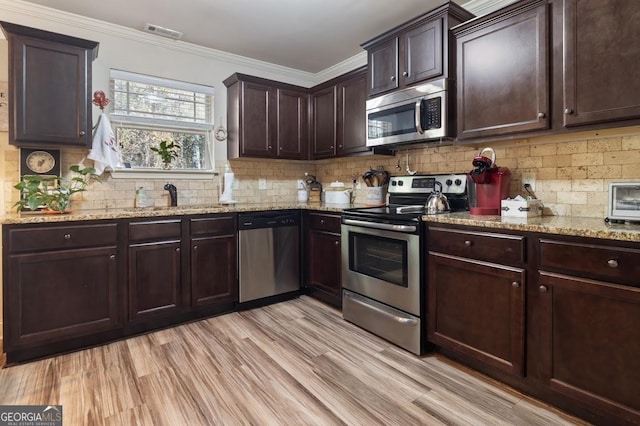 kitchen with sink, crown molding, dark brown cabinets, and appliances with stainless steel finishes