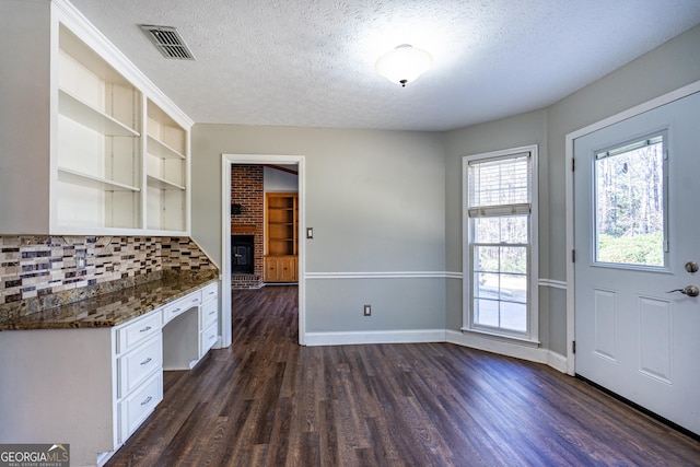 kitchen featuring dark hardwood / wood-style flooring, backsplash, built in desk, and a textured ceiling