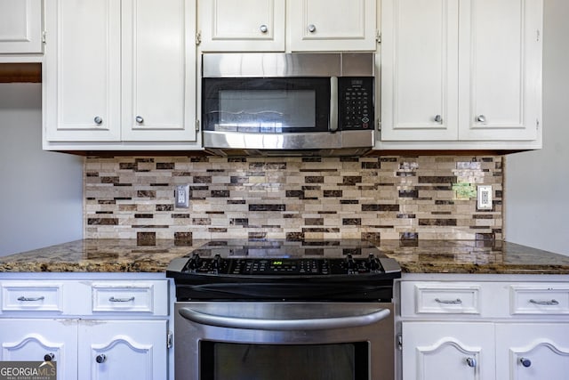 kitchen with white cabinetry, appliances with stainless steel finishes, dark stone countertops, and backsplash