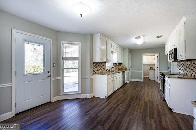 kitchen featuring white cabinetry, stainless steel appliances, dark hardwood / wood-style flooring, and backsplash