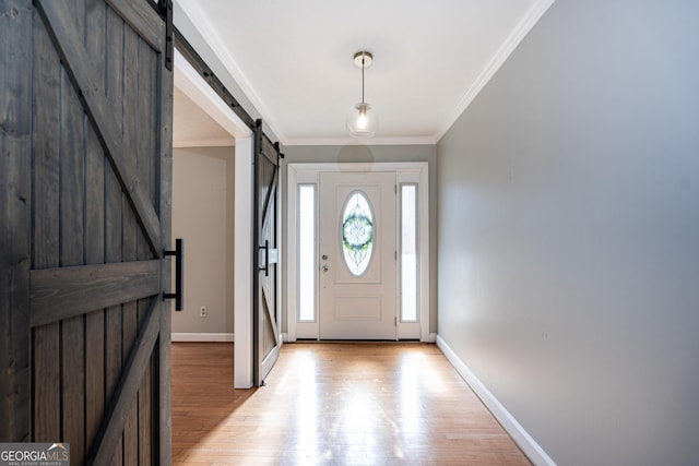 entrance foyer featuring crown molding, a barn door, and light hardwood / wood-style floors