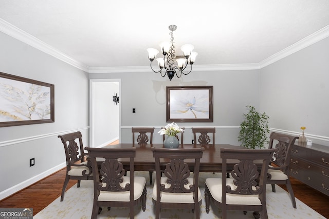 dining area featuring hardwood / wood-style flooring, ornamental molding, and a notable chandelier