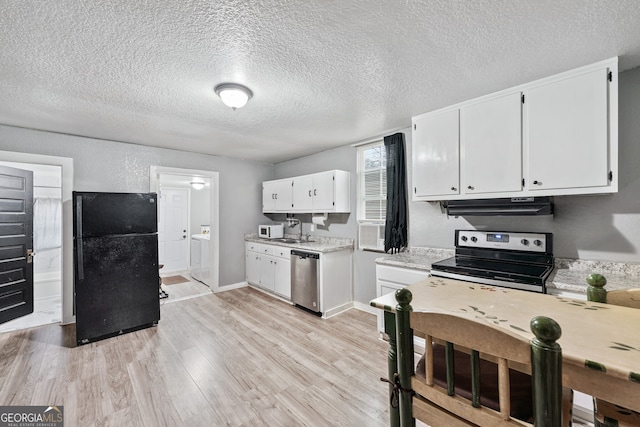 kitchen with washer / dryer, white cabinets, light hardwood / wood-style floors, stainless steel appliances, and a textured ceiling