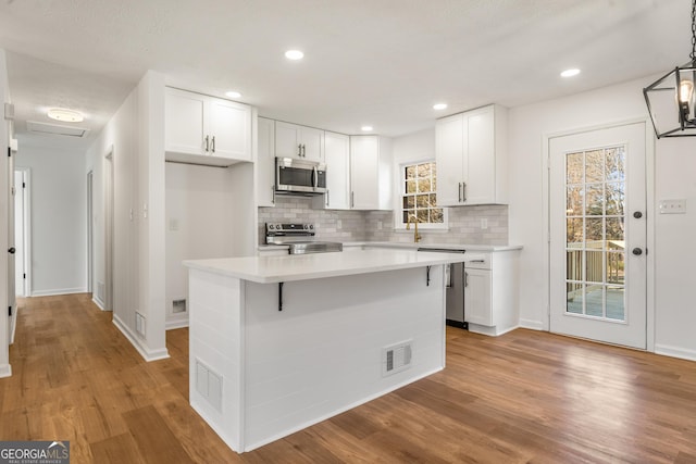 kitchen with pendant lighting, a center island, white cabinets, and appliances with stainless steel finishes