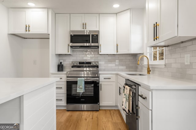 kitchen featuring sink, light hardwood / wood-style flooring, appliances with stainless steel finishes, white cabinetry, and decorative backsplash