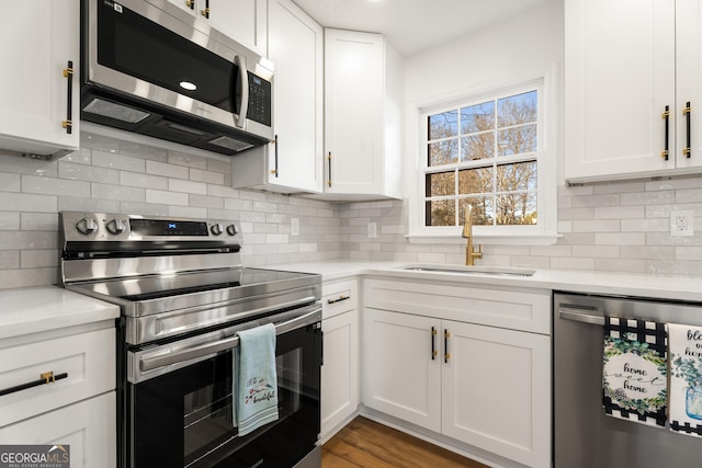 kitchen with sink, white cabinets, backsplash, hardwood / wood-style flooring, and stainless steel appliances