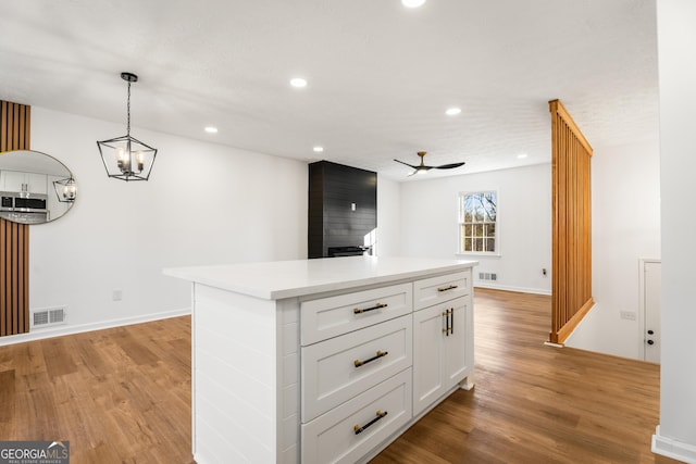 kitchen featuring a kitchen island, pendant lighting, white cabinetry, ceiling fan, and light wood-type flooring