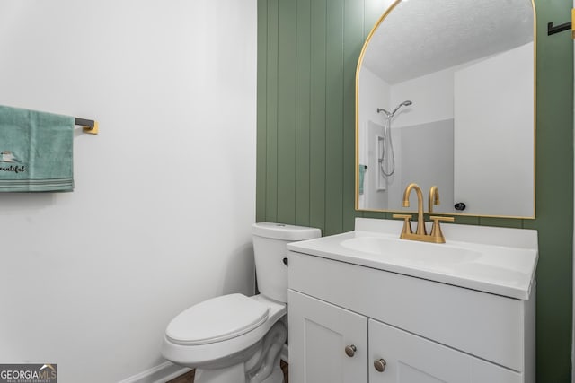 bathroom with vanity, a textured ceiling, a shower, and toilet