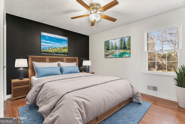 bedroom featuring hardwood / wood-style flooring, ceiling fan, and a textured ceiling