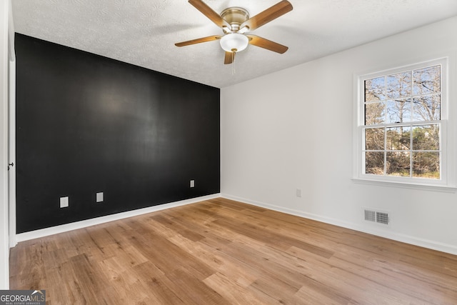 unfurnished room featuring ceiling fan, a textured ceiling, and light wood-type flooring