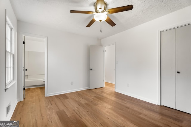 unfurnished bedroom with ceiling fan, a closet, light hardwood / wood-style flooring, and a textured ceiling