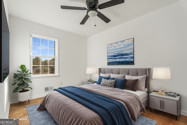 bedroom with ceiling fan, a textured ceiling, and light wood-type flooring