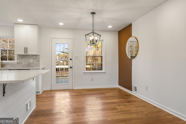 unfurnished dining area featuring a chandelier, a textured ceiling, and light hardwood / wood-style flooring