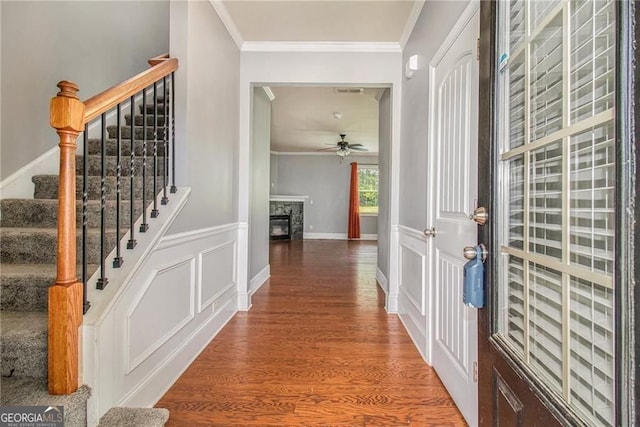 foyer featuring crown molding, a tile fireplace, ceiling fan, and hardwood / wood-style flooring