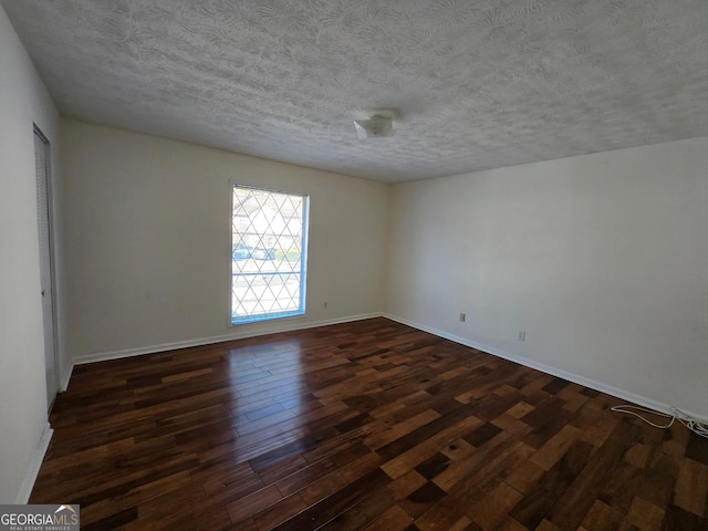 empty room with dark hardwood / wood-style flooring and a textured ceiling