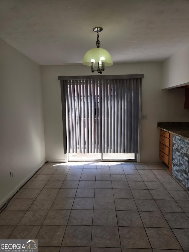 unfurnished dining area featuring a notable chandelier and light tile patterned floors