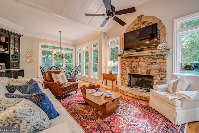 living room featuring ceiling fan with notable chandelier, a fireplace, wood-type flooring, lofted ceiling, and ornamental molding