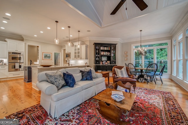 living room with sink, ceiling fan with notable chandelier, ornamental molding, and light wood-type flooring