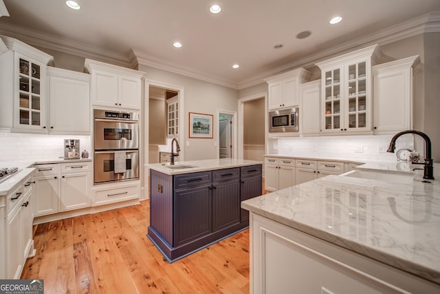 kitchen with stainless steel appliances, sink, a center island with sink, and white cabinets