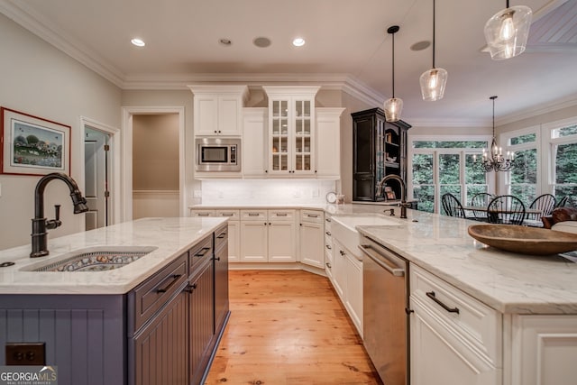 kitchen featuring white cabinetry, appliances with stainless steel finishes, decorative light fixtures, and sink