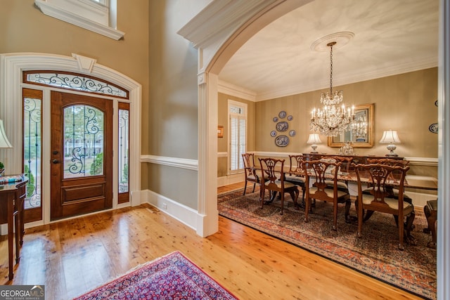 foyer with crown molding, hardwood / wood-style floors, and a notable chandelier