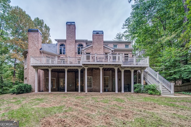 rear view of property featuring a wooden deck and a lawn