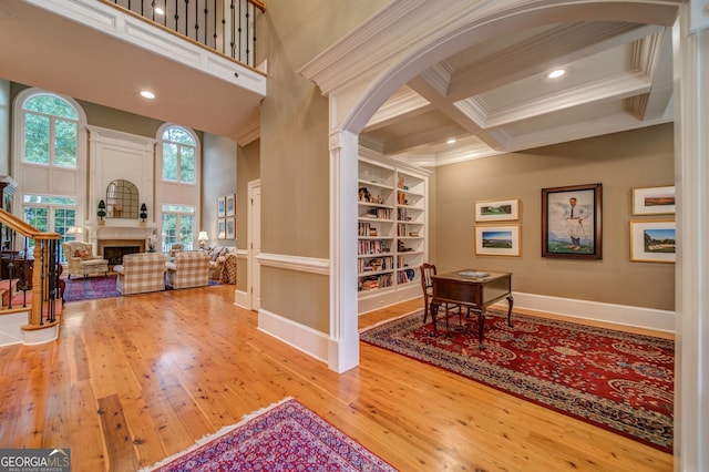 interior space with coffered ceiling, beam ceiling, ornamental molding, and hardwood / wood-style flooring