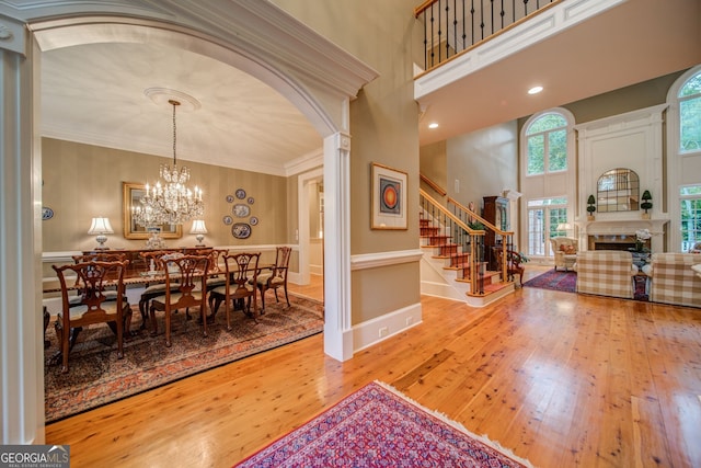 dining space with a towering ceiling, ornamental molding, hardwood / wood-style floors, and ornate columns