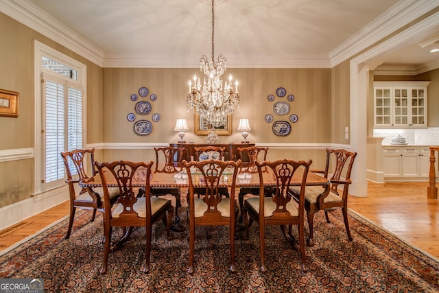 dining space with crown molding, an inviting chandelier, and light hardwood / wood-style flooring