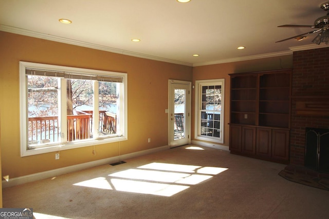 unfurnished living room featuring a fireplace, carpet flooring, visible vents, and crown molding