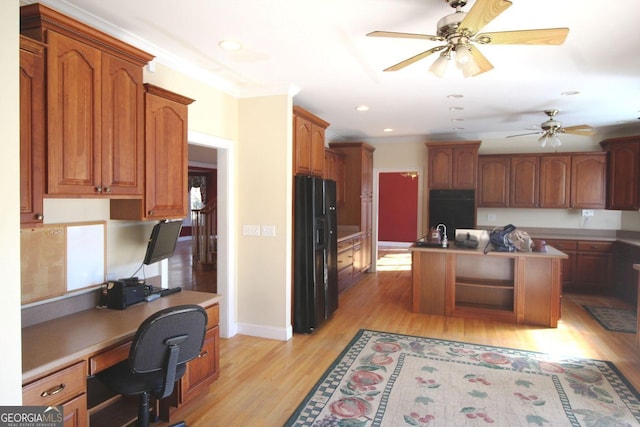 kitchen featuring built in desk, black fridge with ice dispenser, ornamental molding, a kitchen island with sink, and light wood-type flooring